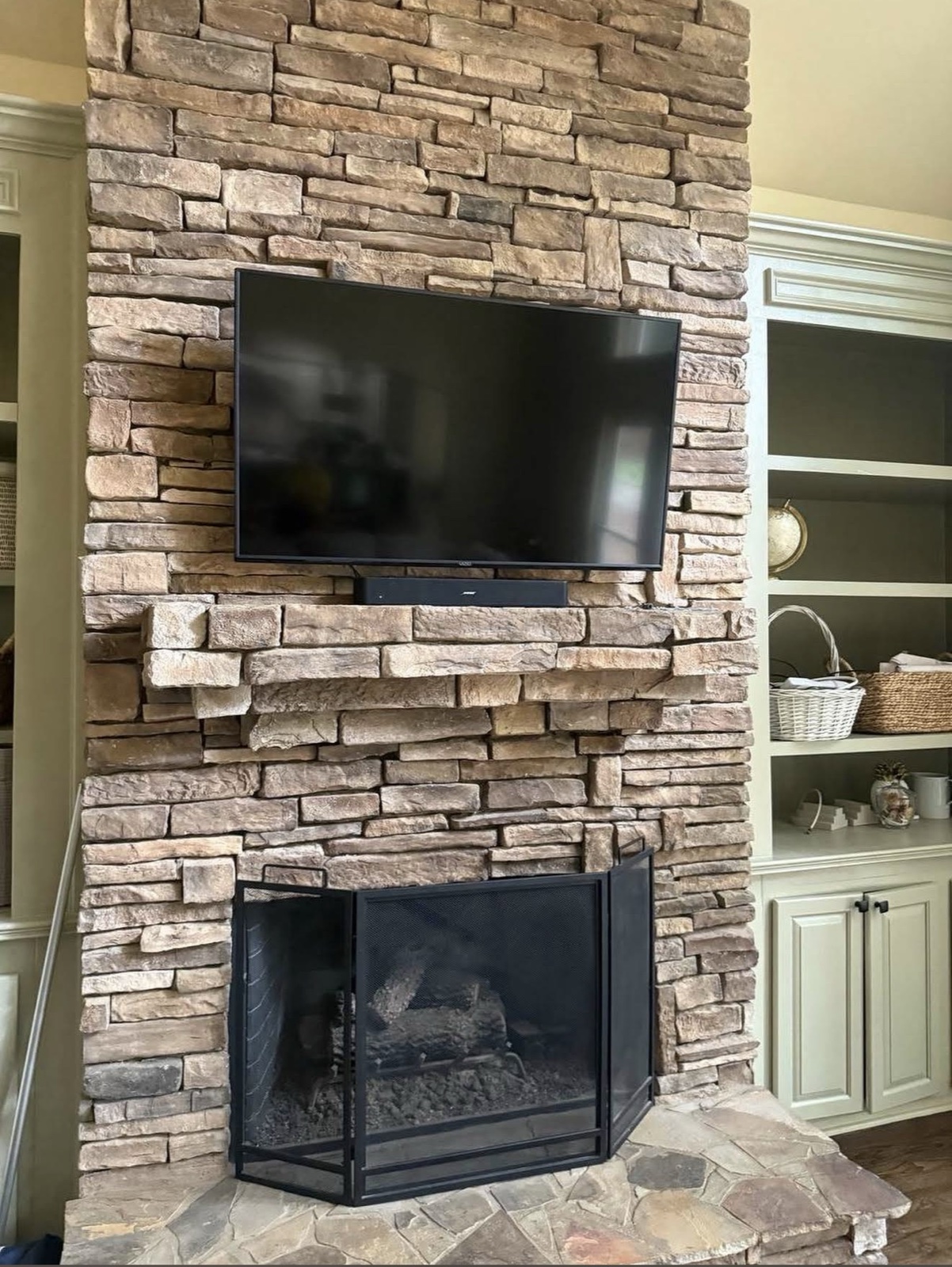 Stone fireplace TV install with built-in shelving
